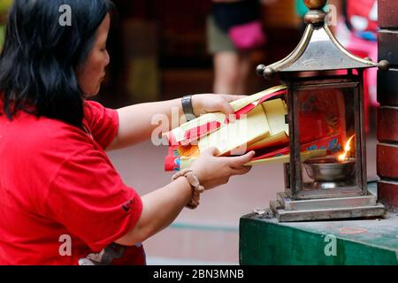 Tempio taoista di Guan di chinese. Donna che brucia carta di joss offerte in forno. Kuala Lumpur. Malesia. Foto Stock