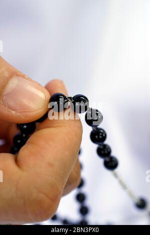 Suino dominicano che paga le perle di rosario. Primo piano sulle mani. Vietnam. Foto Stock
