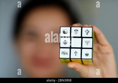 Donna con il cubo di Rubik con simboli religiosi. Concetto di dialogo interreligioso e interreligioso. Foto Stock