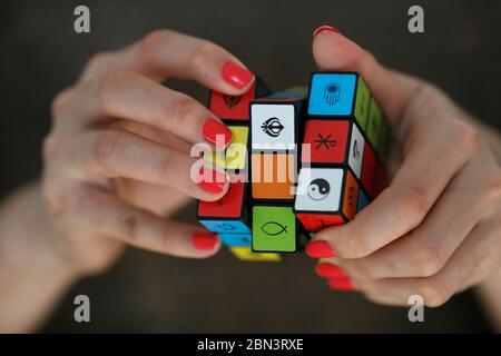 Donna con il cubo di Rubik con simboli religiosi. Concetto di dialogo interreligioso e interreligioso. Foto Stock