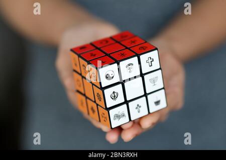 Donna con il cubo di Rubik con simboli religiosi. Concetto di dialogo interreligioso e interreligioso. Foto Stock
