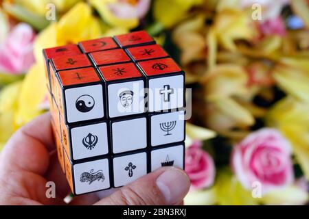 Uomo con il cubo di Rubik con simboli religiosi. Concetto di dialogo interreligioso e interreligioso. Foto Stock