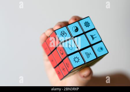 Donna con il cubo di Rubik con simboli religiosi. Concetto di dialogo interreligioso e interreligioso. Foto Stock