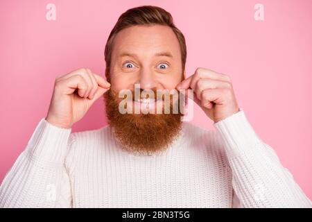 Primo piano del suo bel divertente comico allegro ragazzo rosso allegro che tocca baffi isolato su sfondo rosa colore pastello Foto Stock