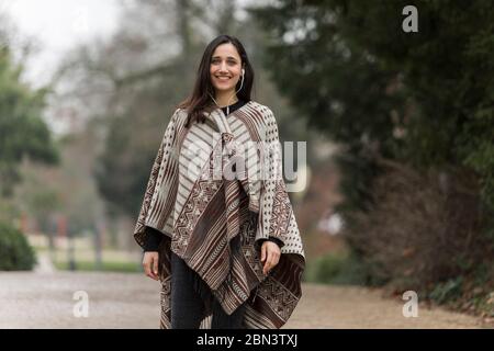 Giovane donna indiana che indossa poncho sorridente sorriso toothy alla macchina fotografica all'aperto. Foto Stock