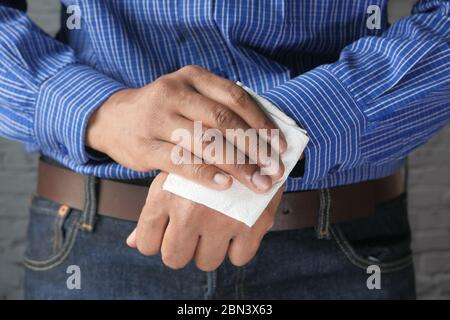 uomo che pulisce le mani con un panno antisettico bagnato. Foto Stock