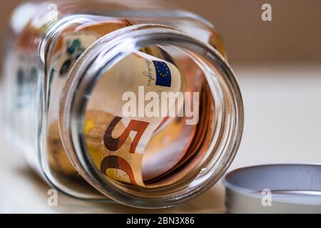 Composizione con banconote di risparmio in un vaso di vetro. Concetto di investimento e di mantenimento del denaro, primo piano isolato. Foto Stock