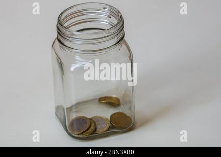 Composizione con monete di risparmio in un vaso di vetro. Concetto di investimento e di mantenimento del denaro, primo piano isolato. Foto Stock