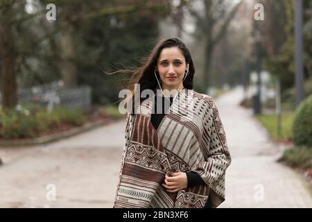 Bella donna medio orientale che indossa poncho in posa all'aperto. Foto Stock