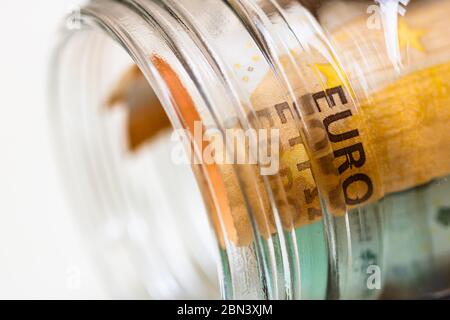 Concetto di investimento e di mantenimento del denaro, primo piano isolato. Composizione con banconote di risparmio in un vaso di vetro. Dettaglio delle banconote in euro in vaso. Foto Stock