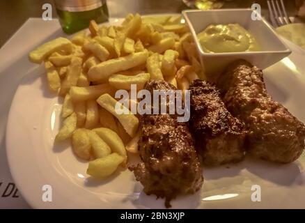 Primo piano di un pasto rumeno composto da salsicce senza pelle a base di carne mista, dette "mici", che sono alla griglia, servite accanto alle patatine fritte e alla tradizione Foto Stock