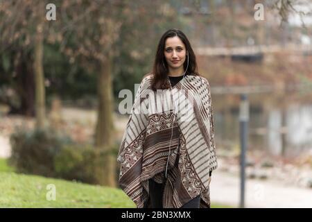 Giovane donna medio orientale modellando poncho nel parco pubblico durante l'autunno. Foto Stock