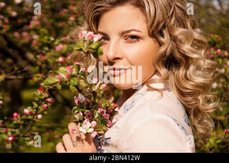 Romantica giovane donna nel giardino primaverile tra i fiori di mela. Bella donna, primavera felice Foto Stock