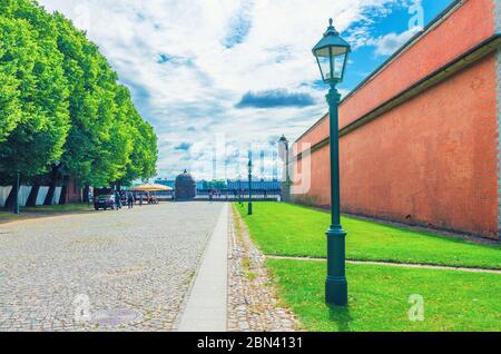 Fortezza muraglia in mattoni, luce di strada e alberi verdi nella cittadella della Fortezza di Pietro e Paolo sull'isola di Zayachy Hare, città di San Pietroburgo Leningrado, Russia Foto Stock