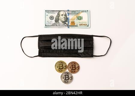 Criptovaluta monete bitcoin fisiche maschera nera e banconota da 100 dollari USA Foto Stock