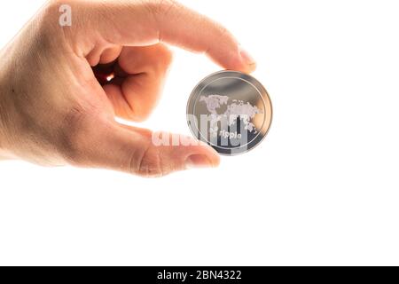Concetto di investimento a ripple e criptovalute. La mano maschio contiene una moneta ondulata in argento Foto Stock