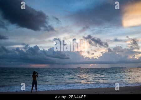 Una donna che viaggia per scattare foto al tramonto in una spiaggia dell'isola di Koh Lanta, in Thailandia. Foto Stock