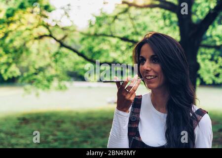 Giovane donna che parla un messaggio vocale su un telefono cellulare Foto Stock