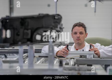 Il tecnico di qualità esegue misurazioni 3D di parti in plastica pressofuse con l'aiuto di un robot per l'industria automobilistica Foto Stock