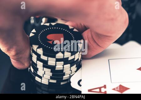 Primo piano di Man Holding pila di chip di Poker in mano con carte vincenti sul tavolo e Diamond Ace in cima. Foto Stock