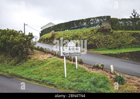 Cartello della città Santo Antonio de Nordestinho in Sao Miguel Island, Azzorre, Portogallo. Strada rurale sulla collina, erba verde, cielo coperto. Parrocchia, villaggio nel comune portoghese. Foto Stock