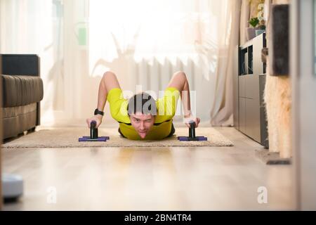 Uomo che fa esercizi push-up utilizzando le barre Push-up a casa. Allenamento fitness. Foto Stock
