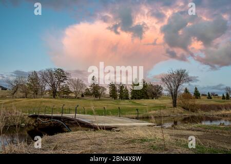 Torreggiante nuvola rosa al tramonto sul Swift Current Creek su un campo da golf a Swift Current, SK, Canada Foto Stock