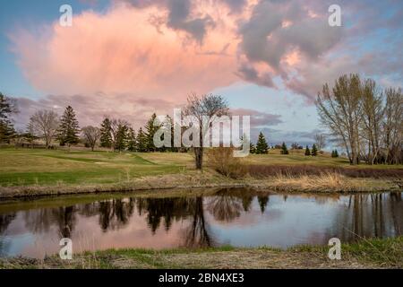 Torreggiante nuvola rosa al tramonto sul Swift Current Creek su un campo da golf a Swift Current, SK, Canada Foto Stock