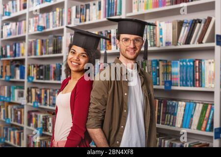 Laureati davanti a una biblioteca. Concetto di preparazione e determinazione Foto Stock