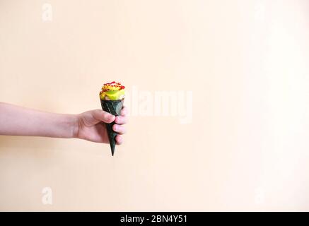 Gelato corno in mano di un bambino su un leggero sfondo monofonico. Foto Stock