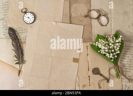 Carta vecchia, penna di piuma, accessori vintage e fiori primaverili. Sfondo nostalgico Foto Stock