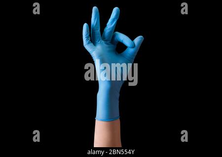 Mano del medico in guanti medici sterili in gesto di OK isolato su nero Foto Stock