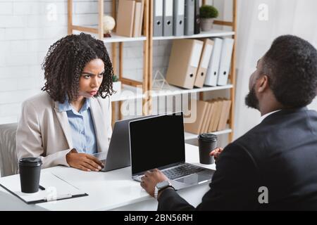 Annoiato African American donna che ha disaccordo con il suo collega sul posto di lavoro, copy space Foto Stock