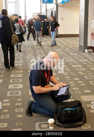 Austin Texas USA, 12 marzo 2012: Partecipante alla conferenza interattiva di South by Southwest si inginocchia nel corridoio dell'Austin Convention Center per utilizzare il suo tablet. ©Marjorie Kamys Cotera/Daemmrich Photography Foto Stock