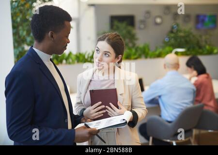 Girovita ritratto di giovane donna d'affari desiderosa che parla con il responsabile mentre discute il progetto di lavoro in ufficio, copia spazio Foto Stock