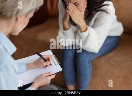 Psicologo prendere appunti parlare con piangendo Donna in ufficio, tagliato Foto Stock