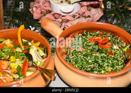 Il tabbouleh è un'insalata vegetariana di Levantine fatta principalmente di prezzemolo tritato finemente. Buffet di brunch con cucina fresca, catering, party con cena, concetto di condivisione Foto Stock