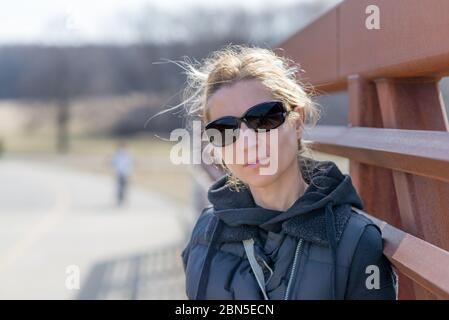 Ritratto di una donna con abiti casual neri in un parco occhiali da sole neri Foto Stock