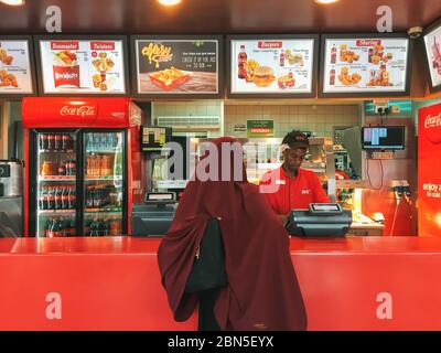 Una donna in un hijab mette un ordine di fast food al banco KFC a Nairobi, Kenya Foto Stock