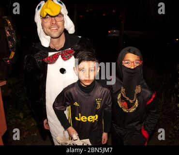 Bambini in costume con il loro pinguino padre fuori per Halloween e trucchi e delizie. St Paul Minnesota, Minnesota, USA Foto Stock