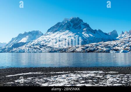 Vulcanica spiaggia di ciottoli neri lungo il Lago Gray (Lago Grigio) in inverno con la cima Paine Grande, Parco Nazionale Torres del Paine, Patagonia, Cile. Foto Stock