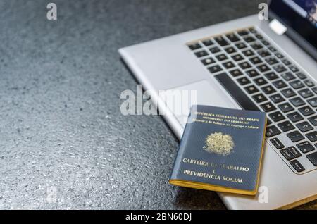 Traduzione: Repubblica Federativa del Brasile, Ministero del lavoro./ scheda di lavoro brasiliana (Carteira de Trabalho) e computer portatile. Foto Stock