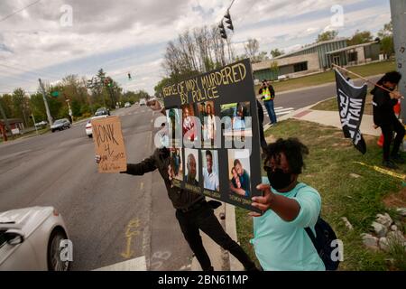 Indianapolis, Stati Uniti. 12 maggio 2020. Un protettore tiene un cartello con le immagini delle persone uccise dalla polizia all'angolo di 62nd Street e Michigan Road vicino a dove un ufficiale del Dipartimento di polizia Metropolitano di Indianapolis ha ucciso a morte Dreasjon Reed, 21, dalla settimana scorsa a Indianapolis. Credit: SOPA Images Limited/Alamy Live News Foto Stock