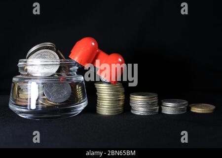 Pila di monete indiane su sfondo nero. Metafora delle imprese, investimento finanziario e concetto economico. Pila di monete indiane in grafico a barre Foto Stock