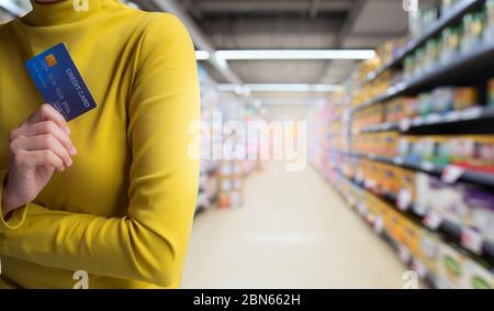 Le mani della donna tengono la carta di credito isolato sullo sfondo del negozio. Foto Stock