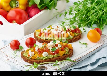 toast all'avocado con feta e pomodori, smorrebrod con ricotta, primo piano Foto Stock