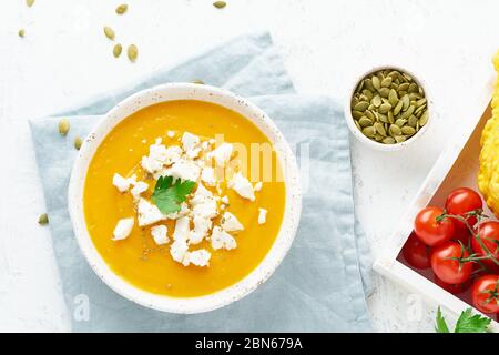 Zuppa di crema di zucca con formaggio feta, cibo fatto in casa d'autunno, sfondo bianco, vista dall'alto Foto Stock