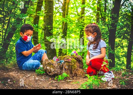 nuovo sfondo normale coronavirus - bambino giocare maschera facciale e sociale di distanza nella foresta per evitare incontri Foto Stock