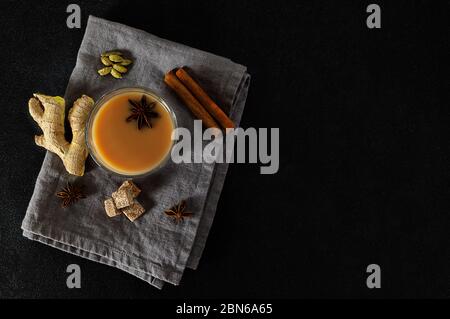 Tazza di vetro di tradizionale tè indiano masala chai su tovagliolo di lino con ingredienti sopra. Foto Stock