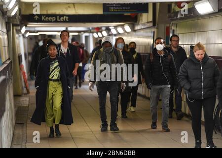 I passeggeri indossano maschere facciali nel sottopassaggio alla stazione Clapham Junction di Londra, dopo l'annuncio dei piani per portare il paese fuori dalla serratura. Foto Stock